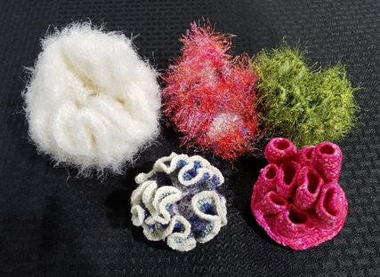 knitted coral reefs in white, red, green, dark gray, and hot pink